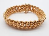 gros plan d'un bracelet en or sur une surface blanche