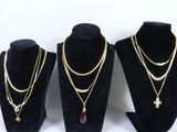 three different necklaces on display on a black display stand