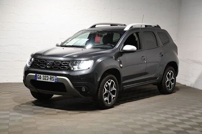La Dacia grise est garée dans un garage dont le sol est en damier.