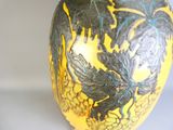 un vase jaune orné de motifs noirs et bleus
