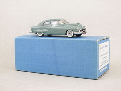 une petite voiture verte posée sur une boîte bleue