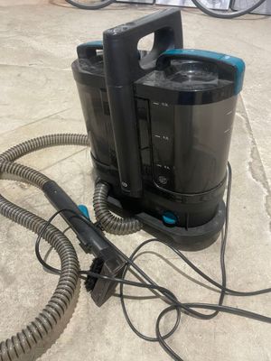 un aspirateur noir et bleu posé par terre à côté d'un tuyau