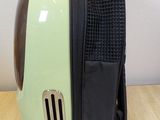 a green and black cat carrier on a wooden table
