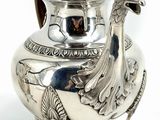 a silver tea pot with a peacock on it