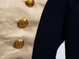 the back of a man ' s coat with gold buttons on it