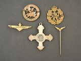 three military badges and a pin on a gray surface