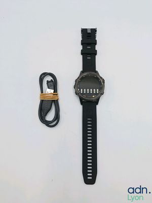 la montre se trouve à côté d'un chargeur et d'un câble