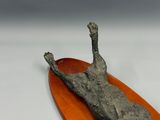 a sculpture of a cat laying on top of a wooden plate