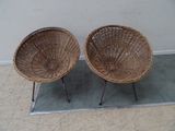 pair of wicker chairs with metal legs on concrete floor