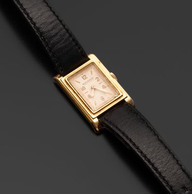 un gros plan d'une montre-bracelet plaquée or montée sur un bracelet en cuir noir