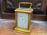 a gold clock sitting on a wooden table in front of a door