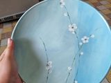 a person holding a blue plate with white flowers on it