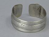 a close up of a silver bracelet with a feather design on it