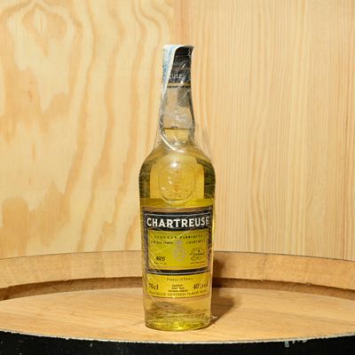 a bottle of alcohol sitting on top of a wooden barrel