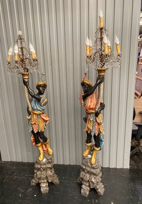 pair of black and gold figurines with a man and a woman holding a chandelier
