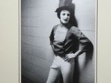 photographie en noir et blanc d'une femme appuyée contre un mur, coiffée d'un haut-de-forme