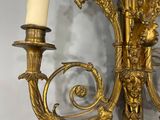 a gold colored sconce with two candles on it