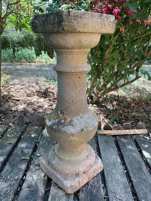 a bird bath sitting on a wooden table in the garden