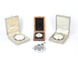 three silver watches are sitting in a wooden box on a white surface