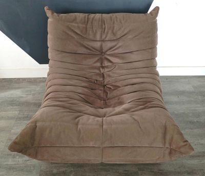 un fauteuil-futon marron dans une pièce avec un parquet et un mur bleu