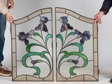 two men are holding stained glass panels with flowers on them