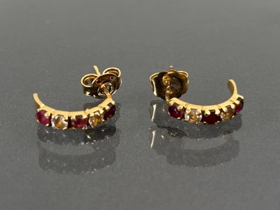 pair of gold and ruby earrings on a black surface