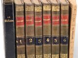 several old books are lined up in a row on a white surface