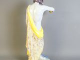 figurine représentant une femme en robe blanche avec un foulard jaune