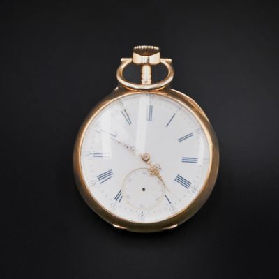 a gold pocket watch with roman numerals on the face
