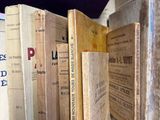 several old books are stacked on a shelf in a room