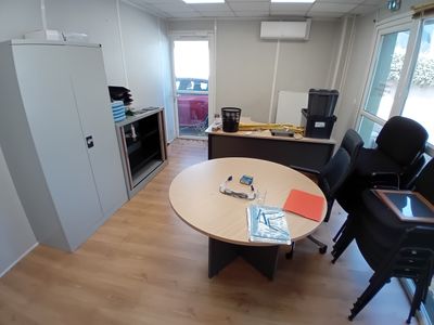 une pièce équipée d'une table, de chaises et d'un réfrigérateur