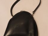 black leather purse on a white surface with a black strap