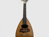 une vieille guitare au corps en bois posée sur une surface blanche