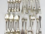 un grand nombre de cuillères et de fourchettes en argent disposées sur une table