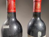 two bottles of red wine sitting next to each other on a table