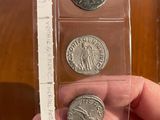 a person holding three different types of coins in a clear box