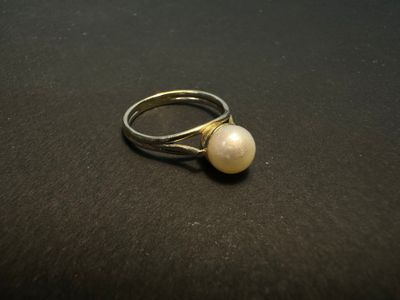 a close up of a ring with a pearl on it