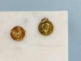 two gold coins sitting on top of a marble slab