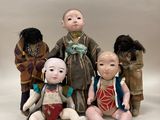 Plusieurs poupées représentant des personnes d'origine asiatique sont disposées en rangée sur un fond blanc.