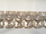 many wine glasses lined up on a shelf next to a window