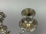 pair of antique silver candlesticks on a stand on a white background