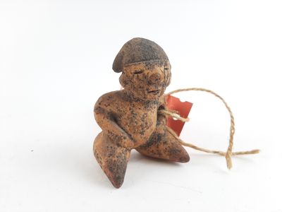a small figurine sitting on a white surface with a string