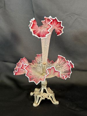 un vase en verre orné de fleurs rouges, posé sur un socle