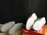 pair of white shoes sitting on top of a box on a wooden table