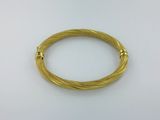 gros plan d'un bracelet en or sur une surface blanche