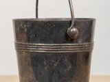 an old metal bucket sitting on top of a wooden table