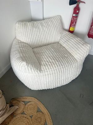 une chaise blanche et un extincteur dans un coin de la pièce