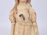 une poupée à l'ancienne aux cheveux blonds, vêtue d'une robe et de chaussures