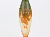 un vase orange et vert posé sur une surface blanche