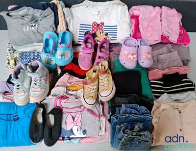 une pile de vêtements et de chaussures pour bébé posée sur une table